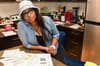  A woman leans on her kitchen counter with paper